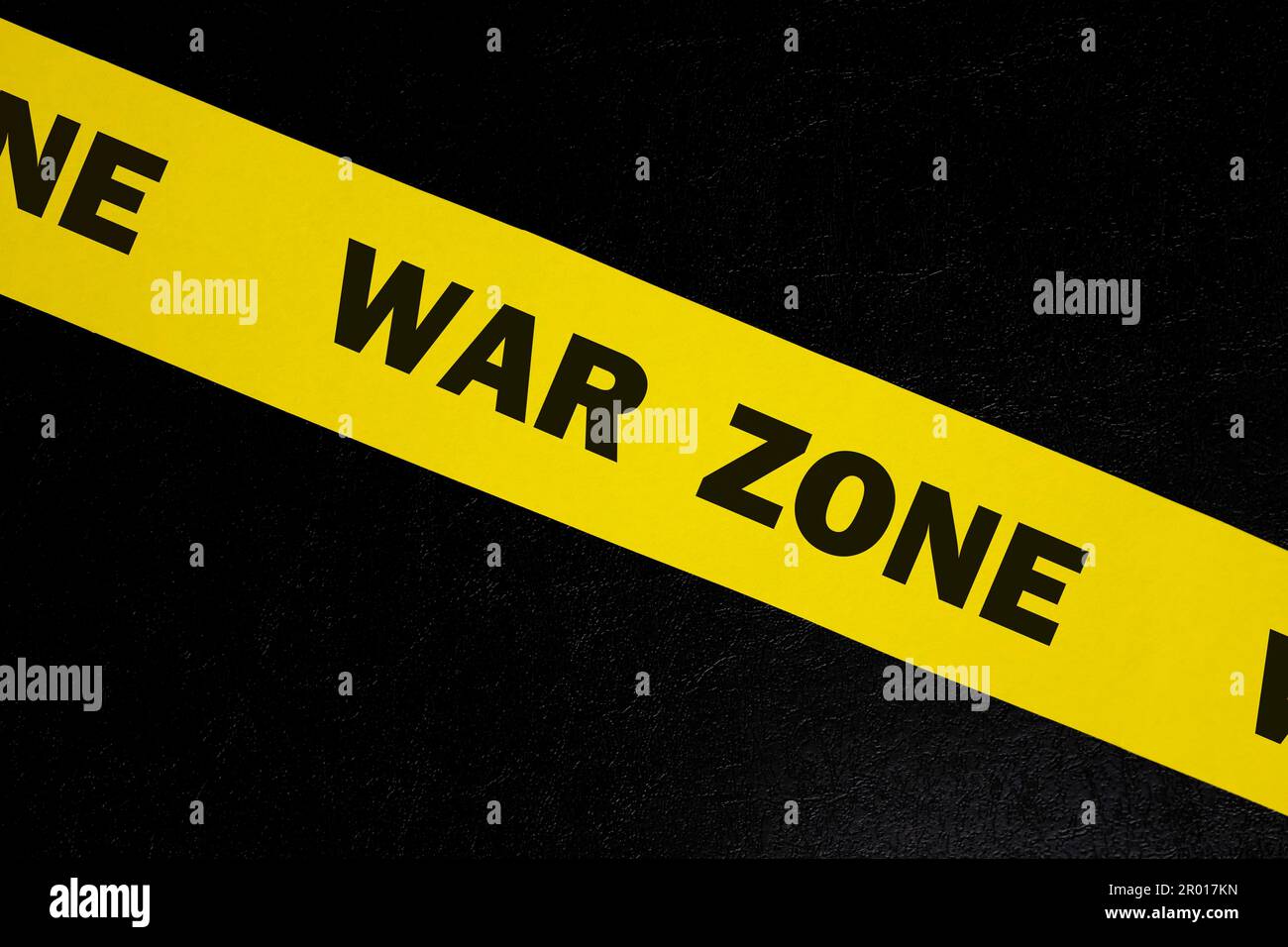 War zone caution and warning concept. Yellow barricade tape with word in dark black background