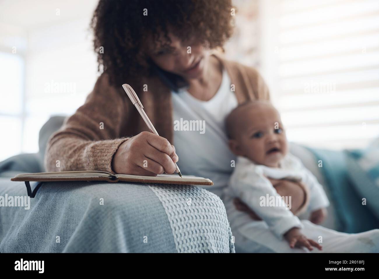 Doing it all for her daughter. a young woman using a smartphone and ...