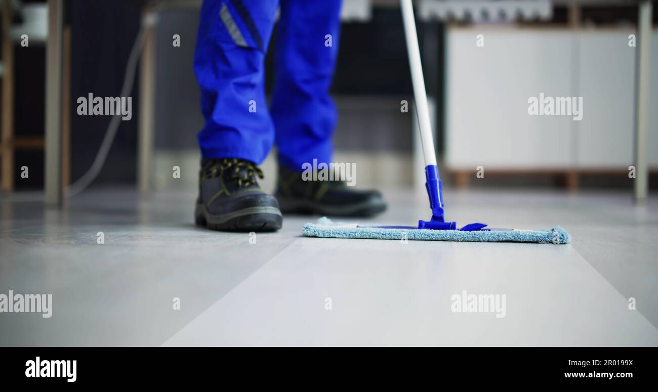 Portrait Of Happy Male Janitor Cleaning Floor At Office Stock Photo