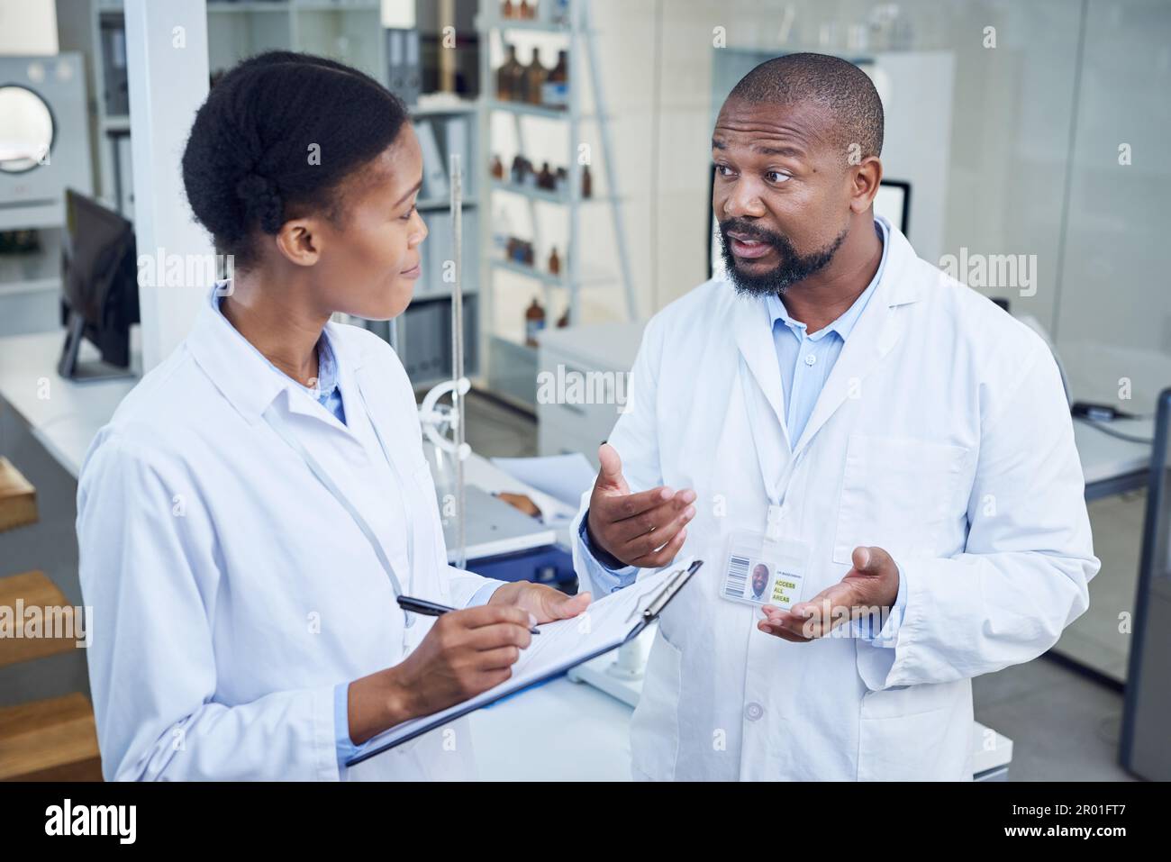 Ensuring they have everything under control. two scientists having a discussion in a lab. Stock Photo