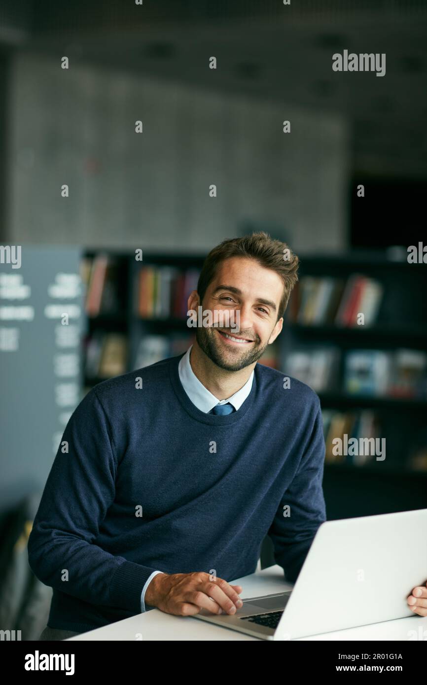 Traditional books have led us to the internet. Cropped portrait of a handsome young businessman sitting alone in a library and using his laptop. Stock Photo