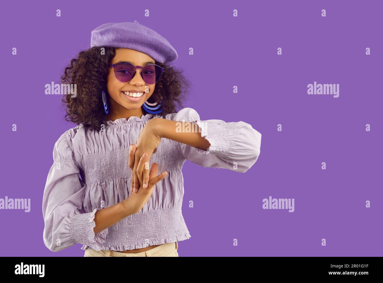 Happy Afro American girl in trendy purple outfit posing in modern fashion studio Stock Photo