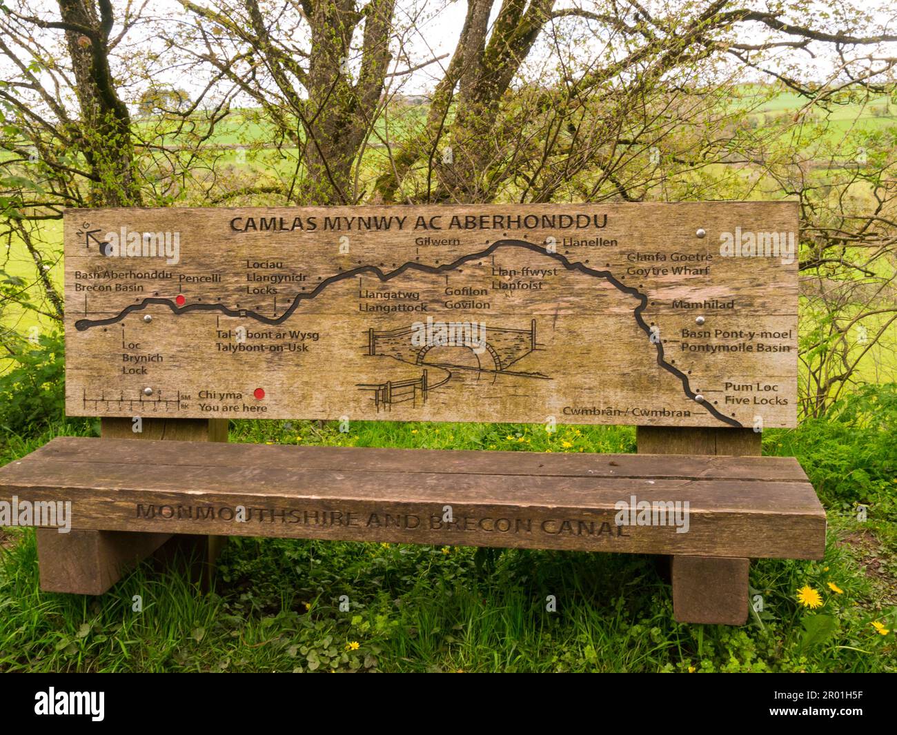 Wooden seat at side of Monmouthshire and Brecon Canal at Pencelli Powys Mid Wales UK showing a carved map of part of  canal's route from Brynich Lock Stock Photo