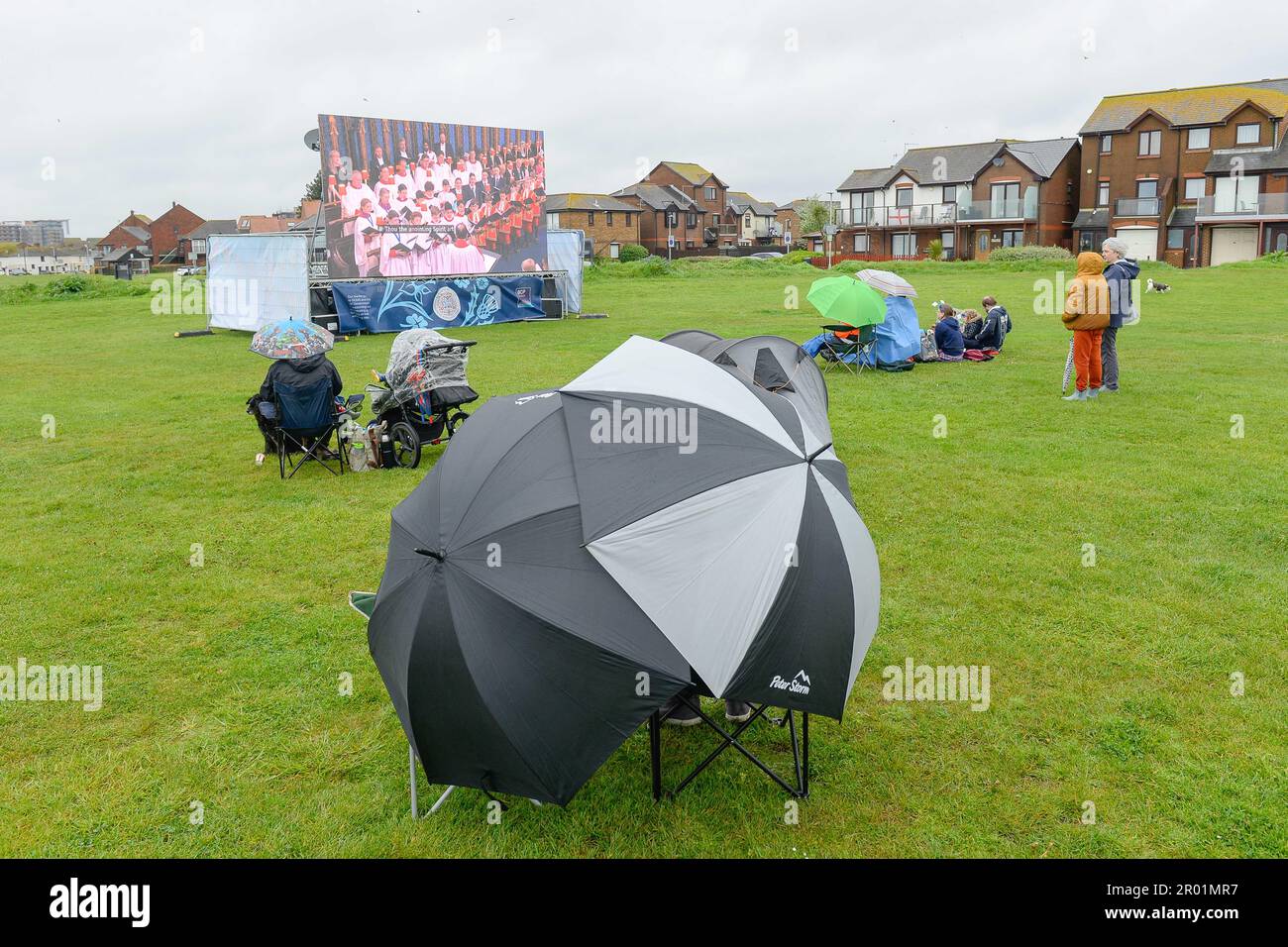 Poole, Dorset, UK.  6th May 2023.  UK Weather.  Coronation revellers wearing waterproofs and with umbrellas brave the rain to watch the Coronation of King Charles III on a big screen at Baiter Park at Poole in Dorset.  Picture Credit: Graham Hunt/Alamy Live News Stock Photo