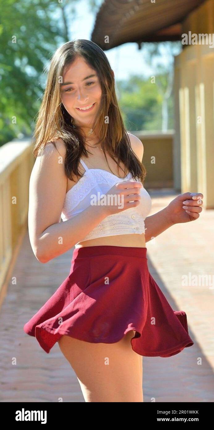 Happy young brunette teenage girl wearing a crop-top and a mini-skirt dances on a hotel balcony.  MODEL RELEASED Stock Photo
