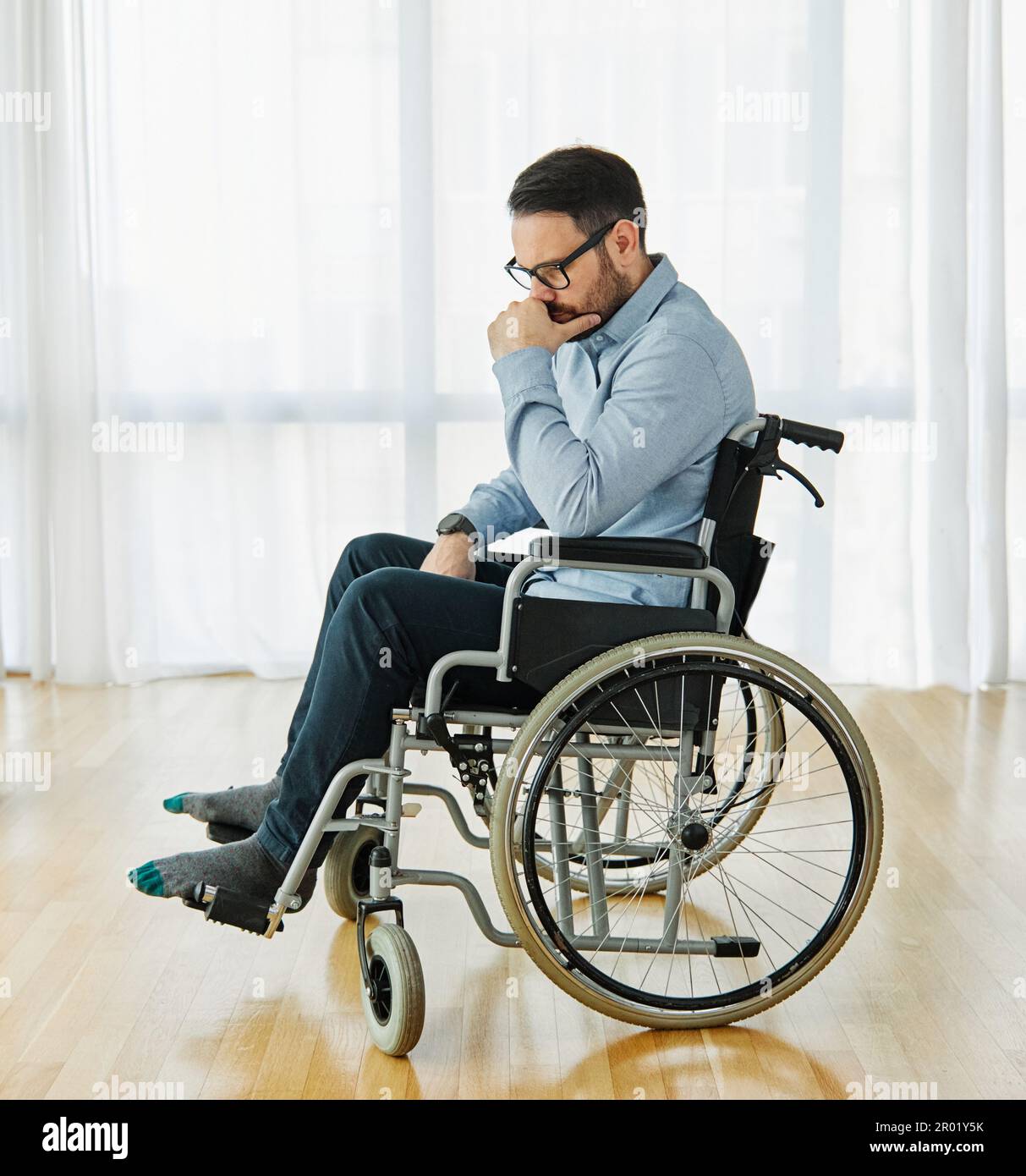 disability wheelchair disabled man handicap sitting handicapped health young wheel care invalid depressed lonely sad alone solitude worried Stock Photo