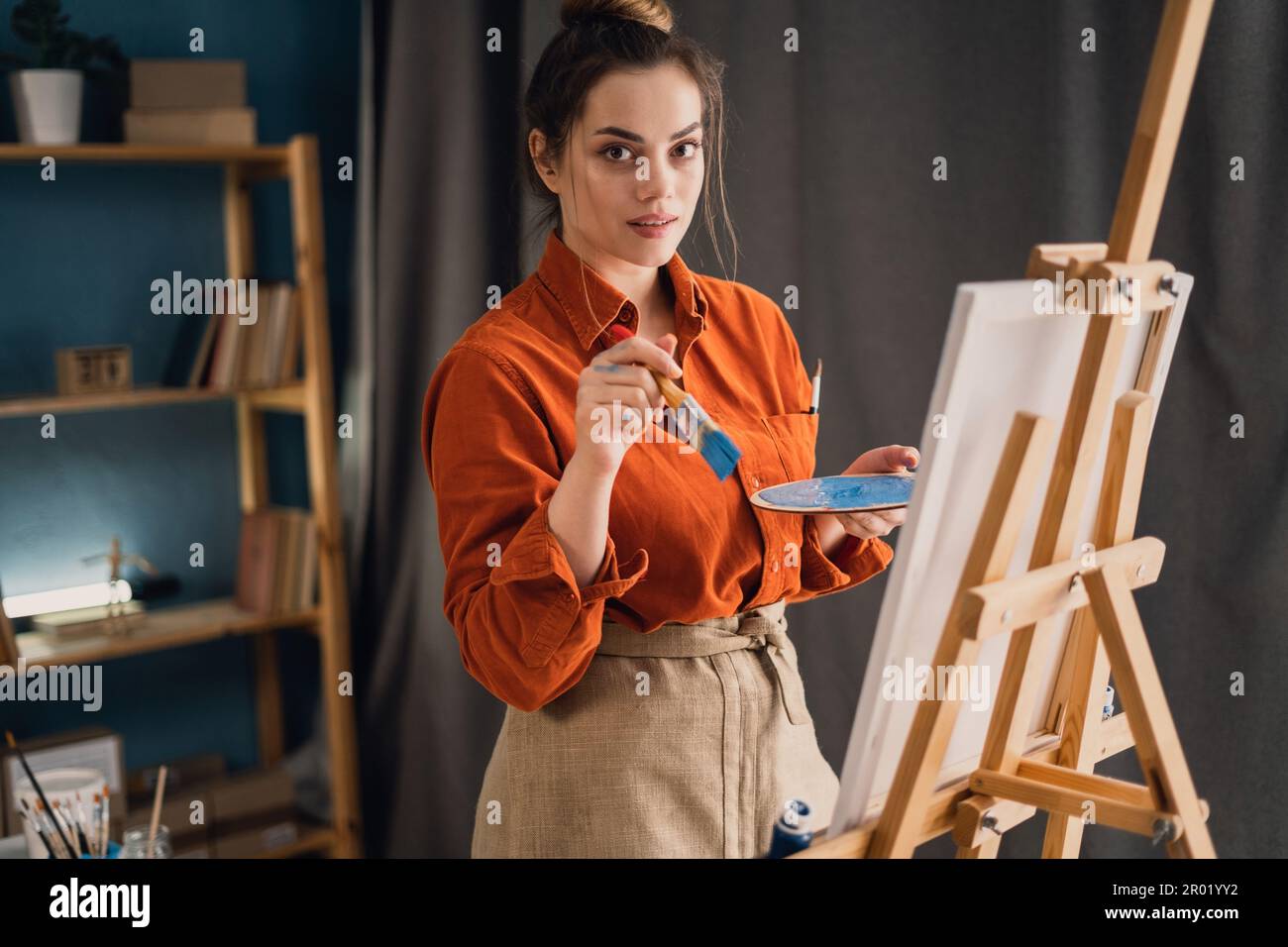 Creative latin female artist standing working on a new painting. Happy