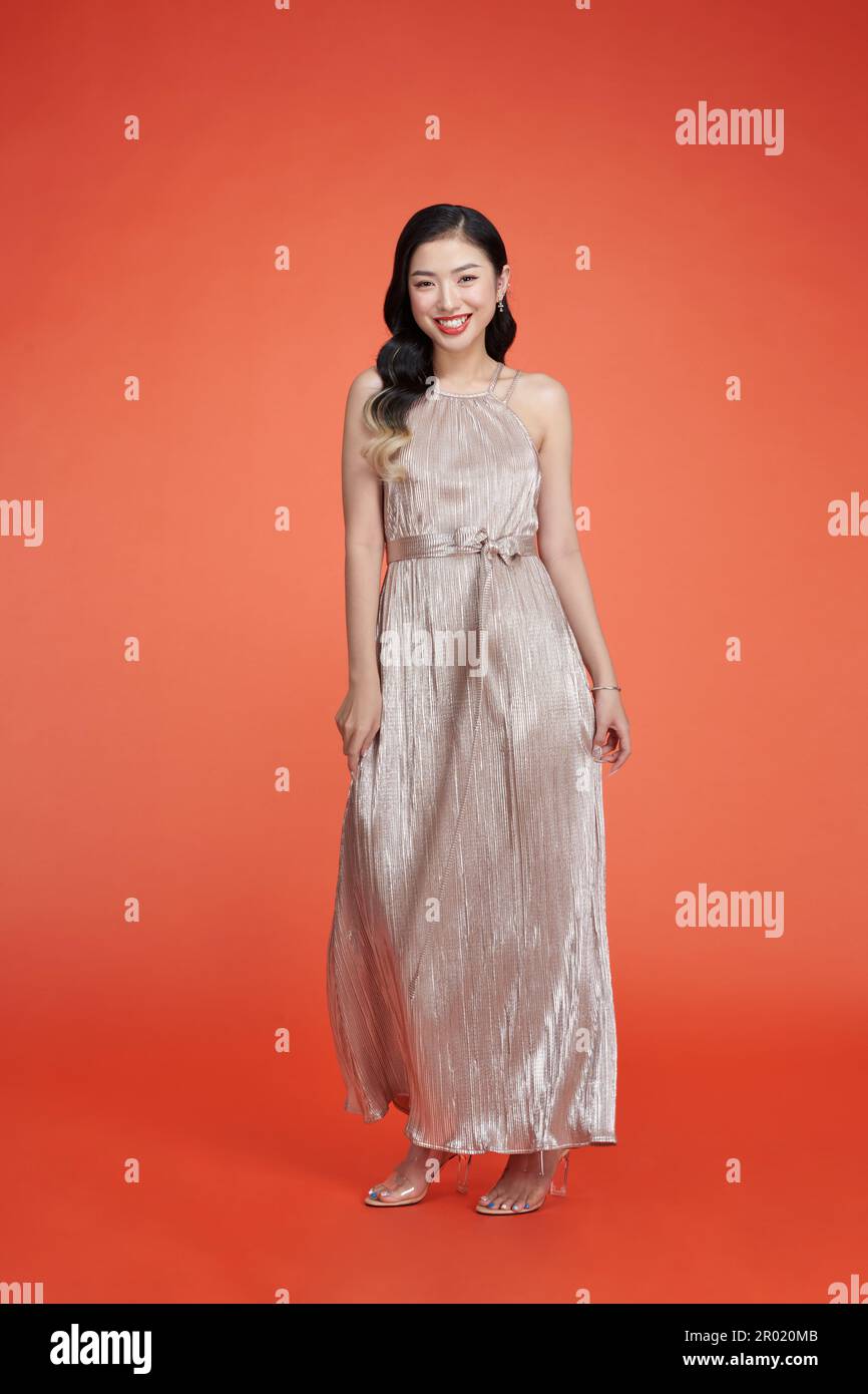 Beautiful model posing in a long sparkling golden gala dress Stock