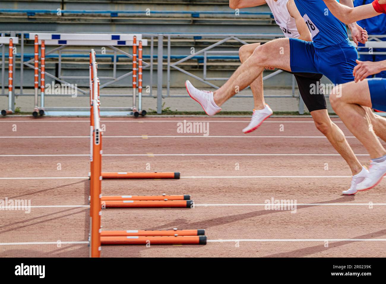 three athlete runners running together 100 meters hurdles race in