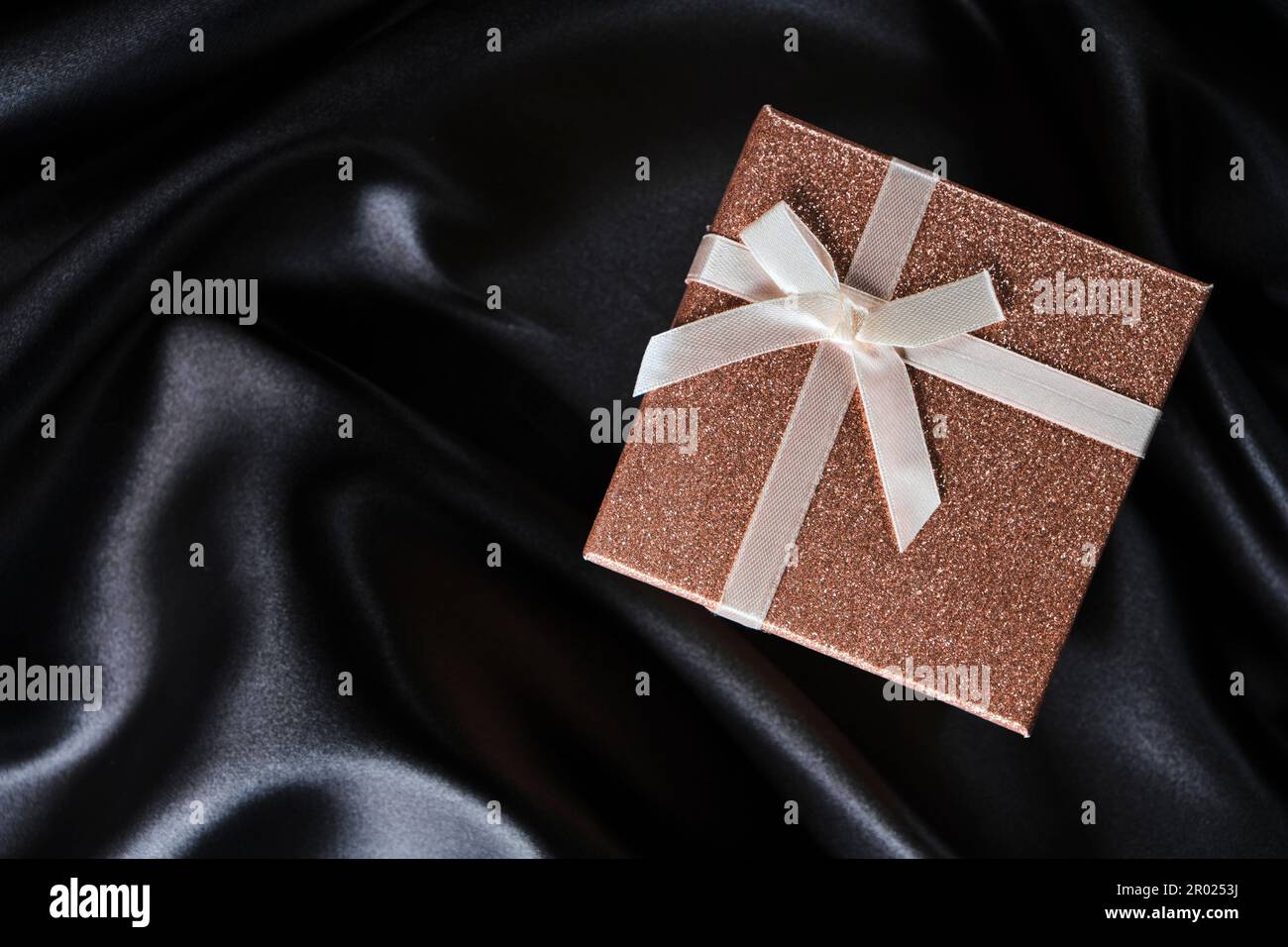 Pink gift box with bow background with black silk fabric Stock Photo ...