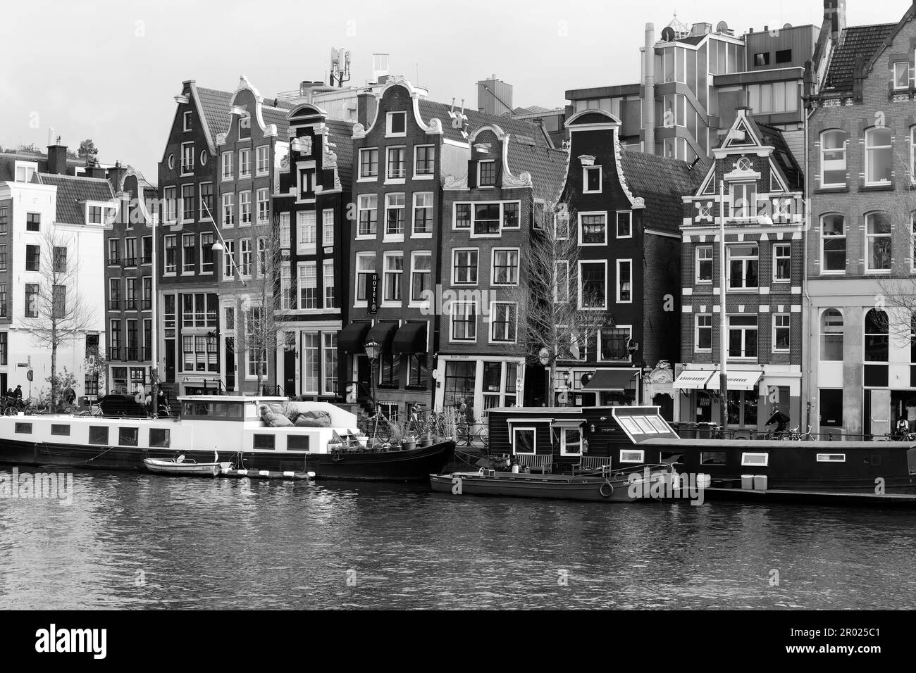 Traditional Dutch canal side housing architecture with moored boats in black and white, Amsterdam, Holland. Stock Photo