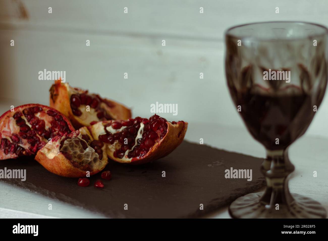 https://c8.alamy.com/comp/2R028F5/pomegranate-with-glass-of-wine-on-table-cut-pomegranate-with-seeds-and-red-wine-fruits-and-wine-summer-still-life-alcohol-drinks-and-ripe-fruits-2R028F5.jpg