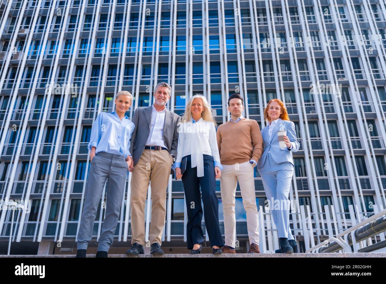 Portrait of cheerful group of coworkers walking outdoors in a corporate office area, Caucasian middle age group Stock Photo