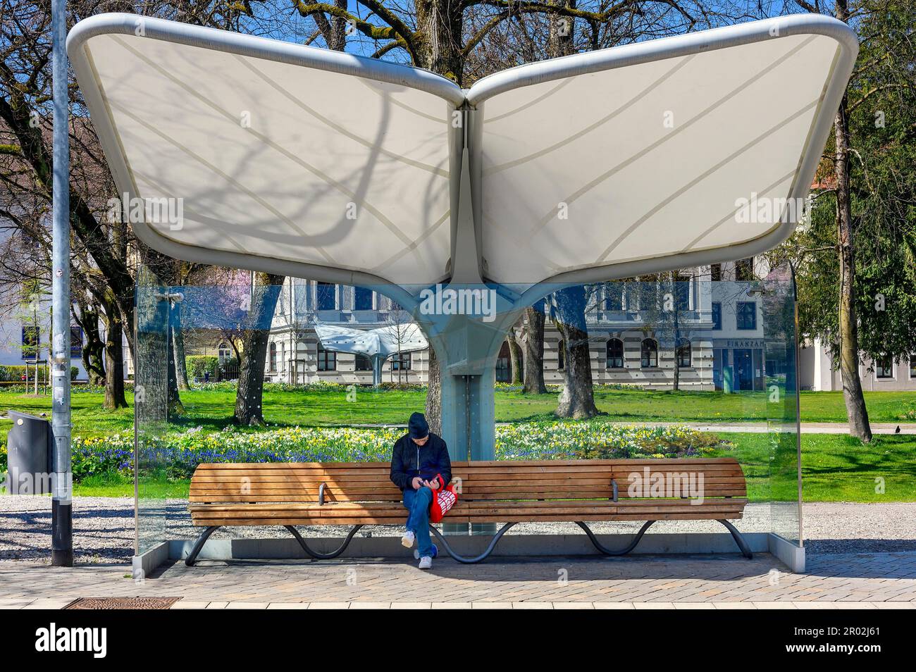 Rain and sun protection over park bench and man with knitted cap, Kempten, Allgaeu, Bavaria, Germany Stock Photo