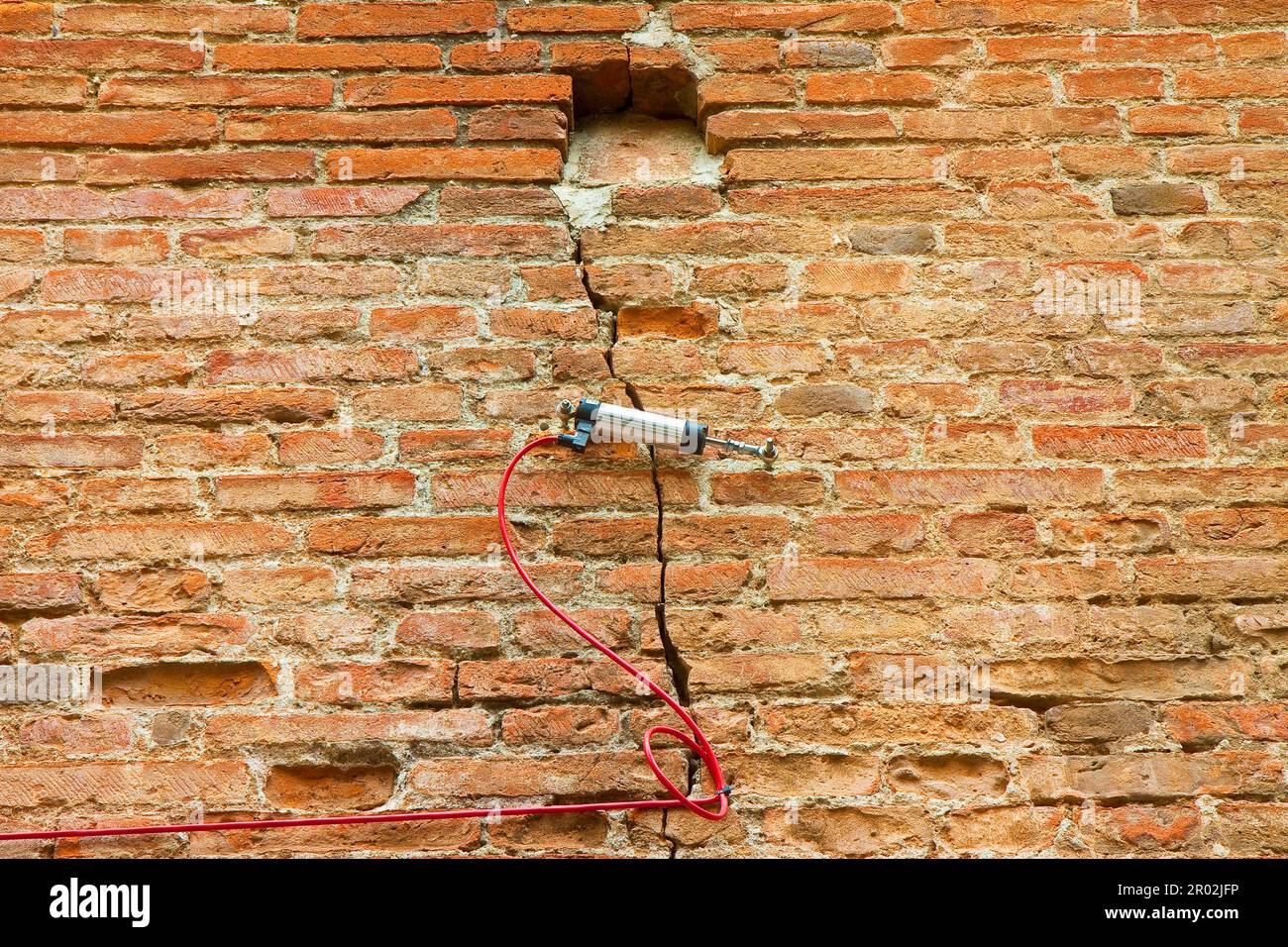 Electric digital crack measuring device reading, by cable, the minimal deformation and movement of a dangerous cracked brick wall Stock Photo