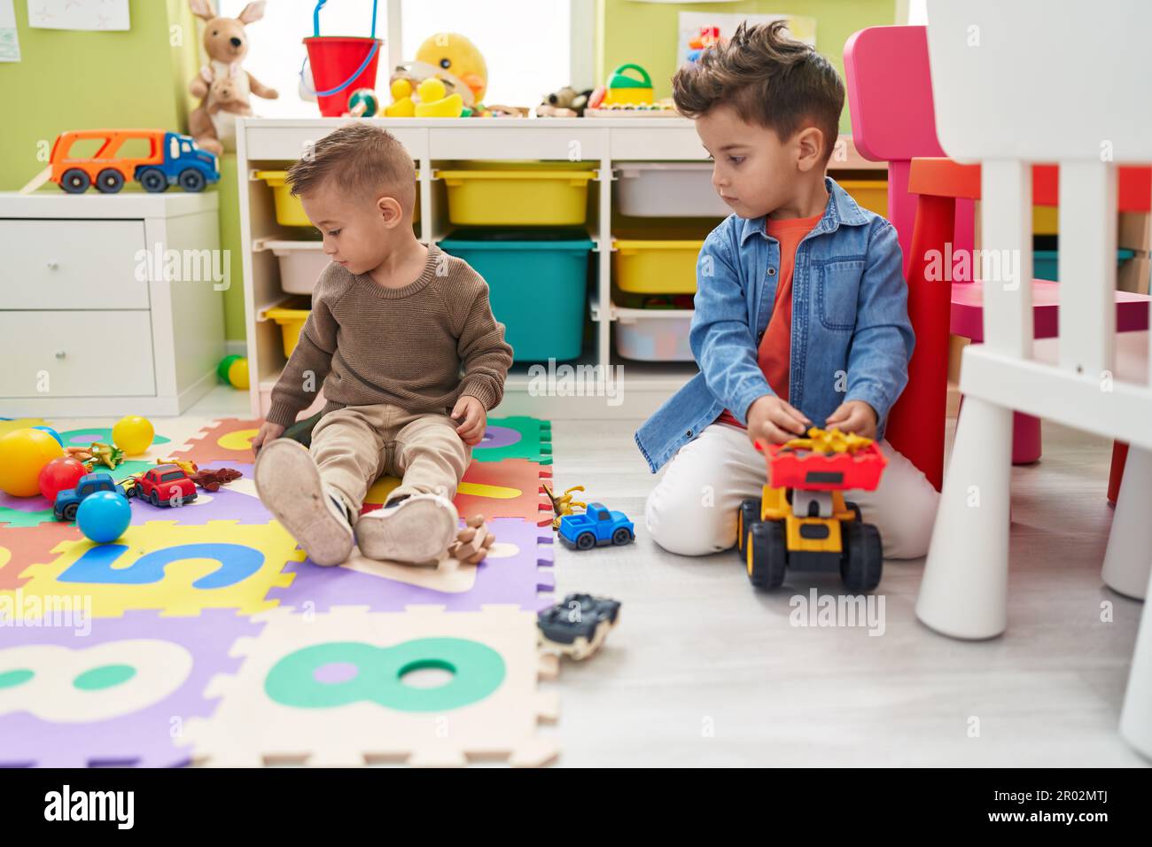Adorable boys playing with cars toy and tractor sitting on floor at ...