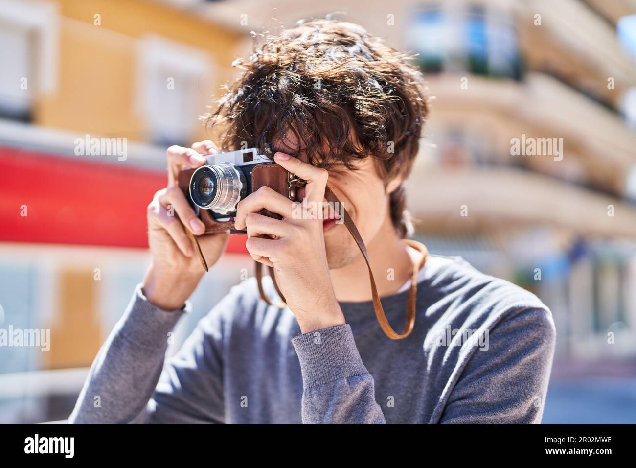 Young hispanic man smiling confident using vintage camera at street Stock Photo