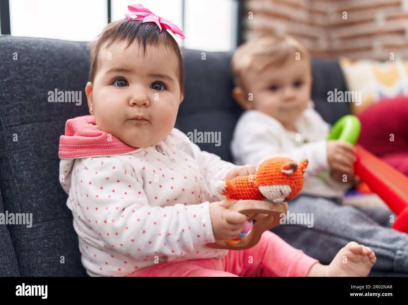 Adorable boy and girl playing with hoops game sitting on sofa at home ...