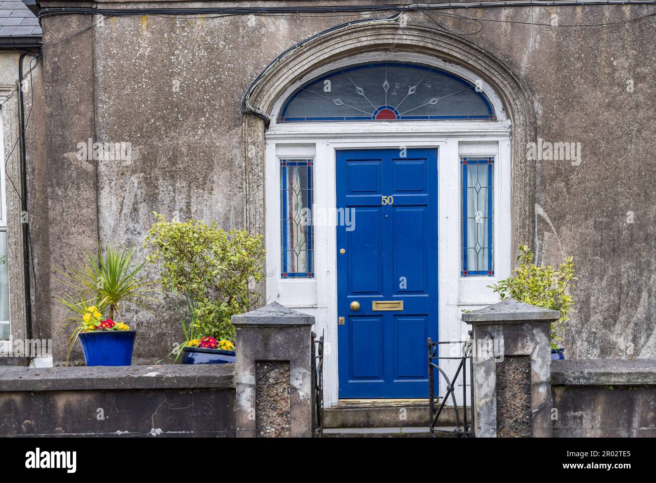 Ornamental front yard with blooming flower pots surrounded by walls and