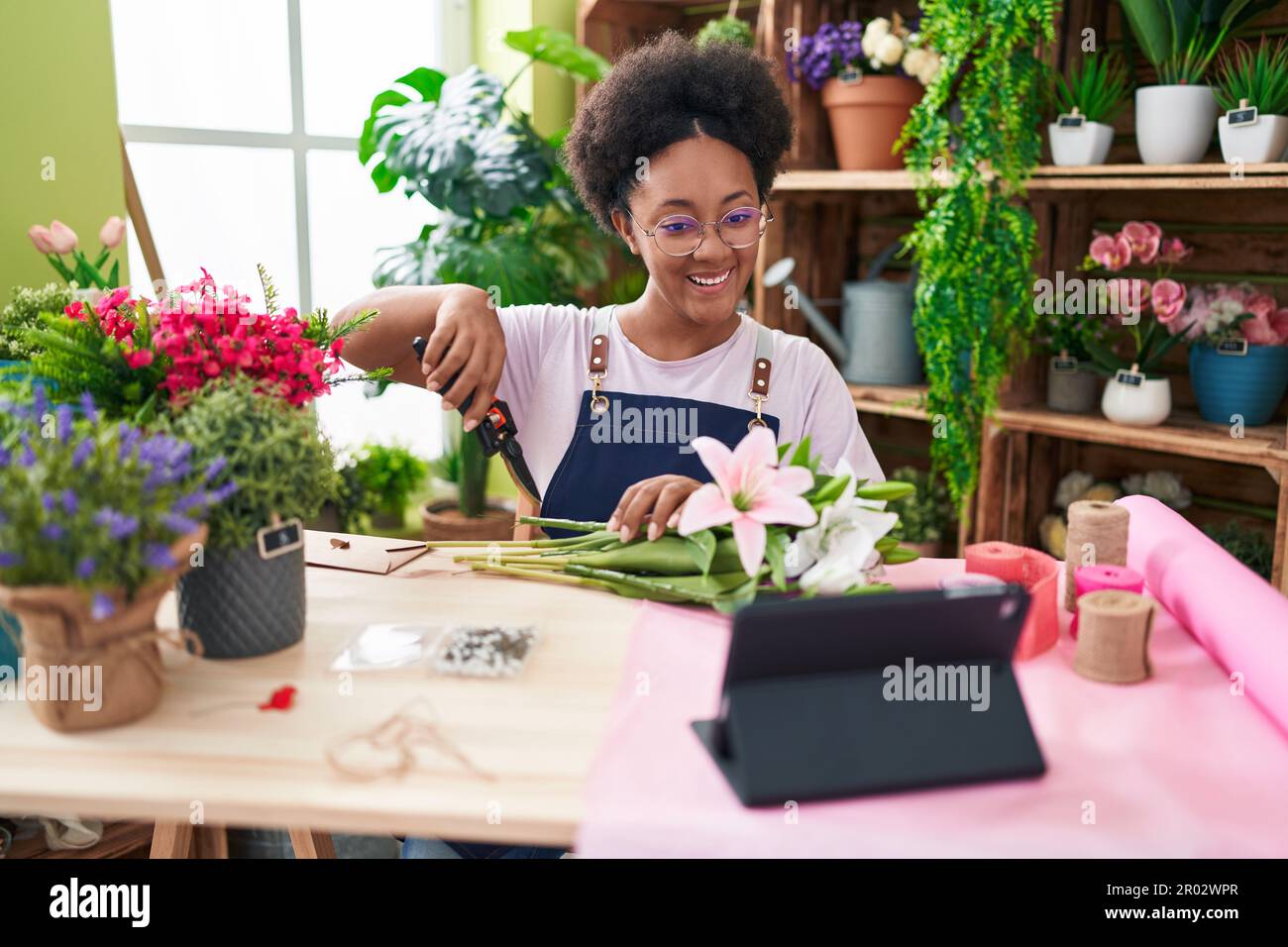 African american woman florist make bouquet of flowers watching video ...