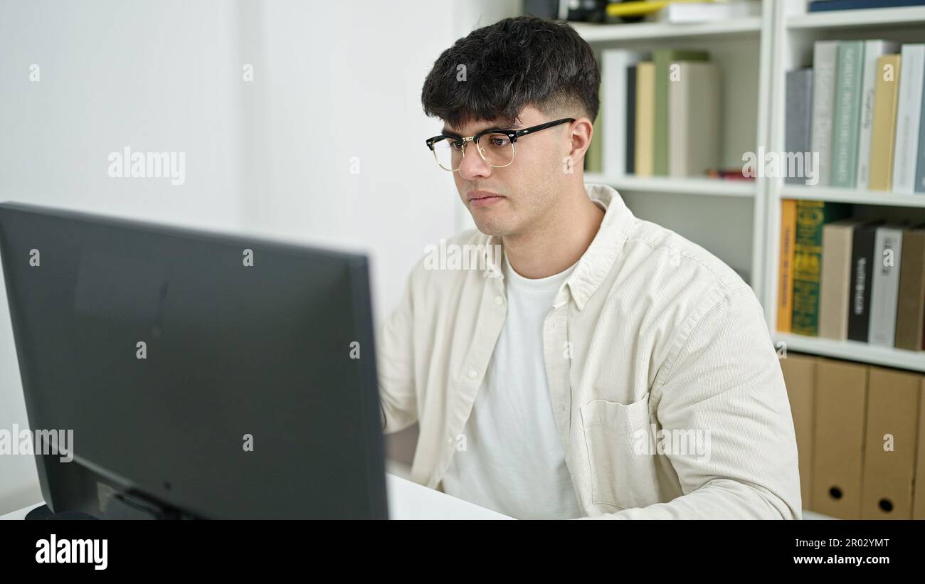 Young hispanic man student using computer studying at library ...