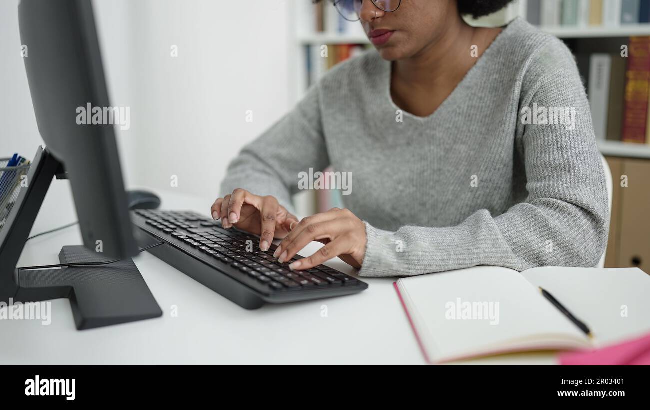 African american woman student using computer studying at library ...