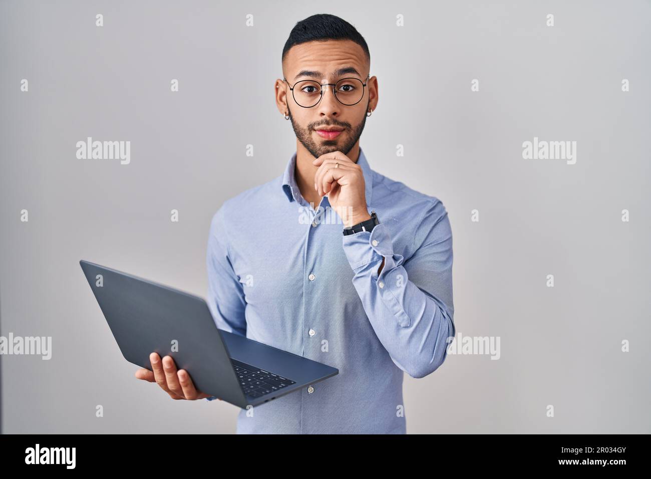 Hispanic Man Using Computer Young hispanic man working using computer laptop looking confident at ...