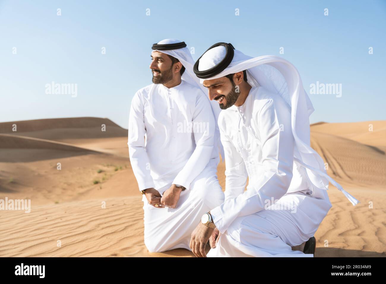 Middle eastern man wearing traditional clothes on desert dune, Dubai,  United Arab Emirates stock photo