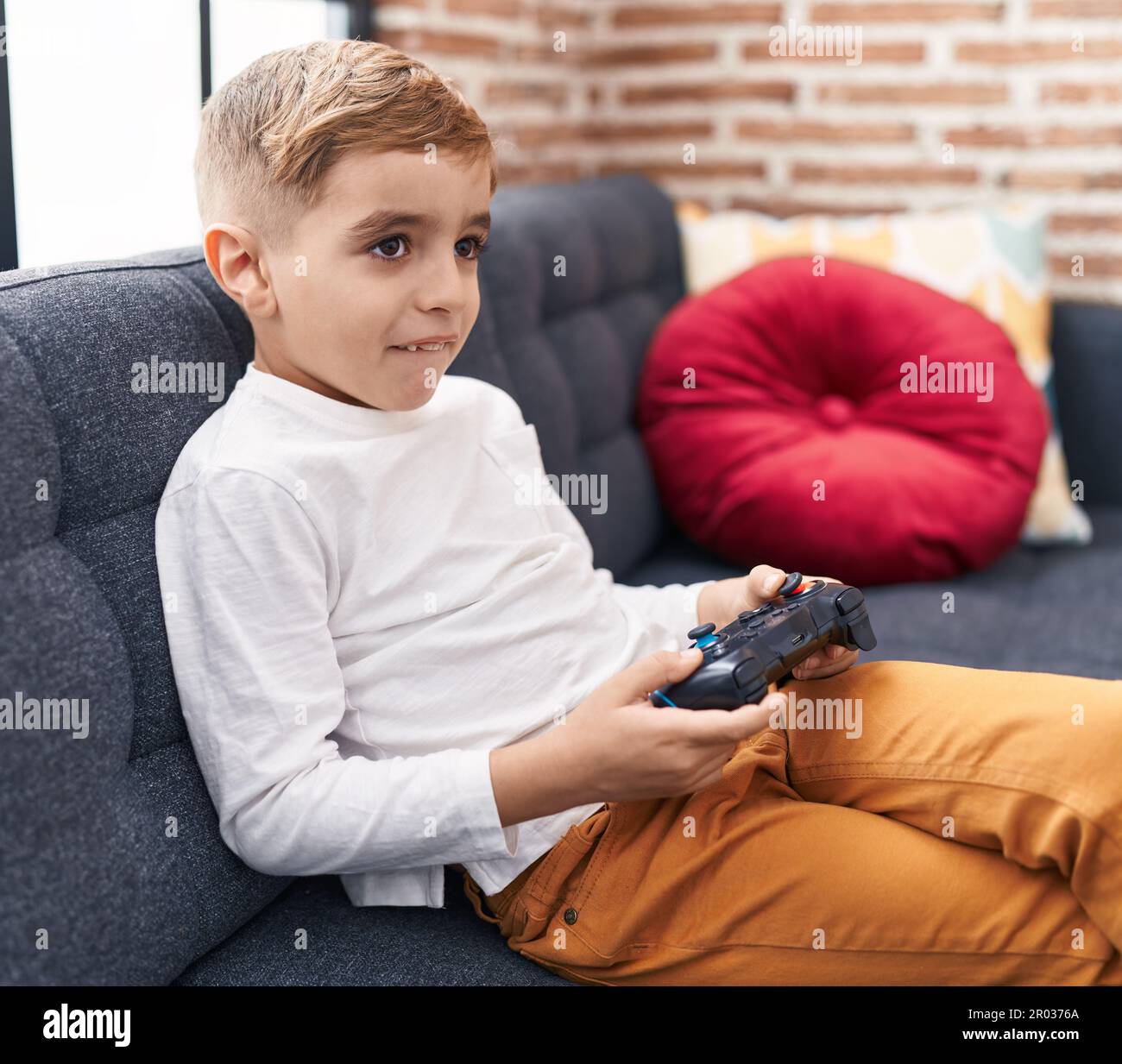 Adorable hispanic boy playing video game sitting on sofa at home Stock ...