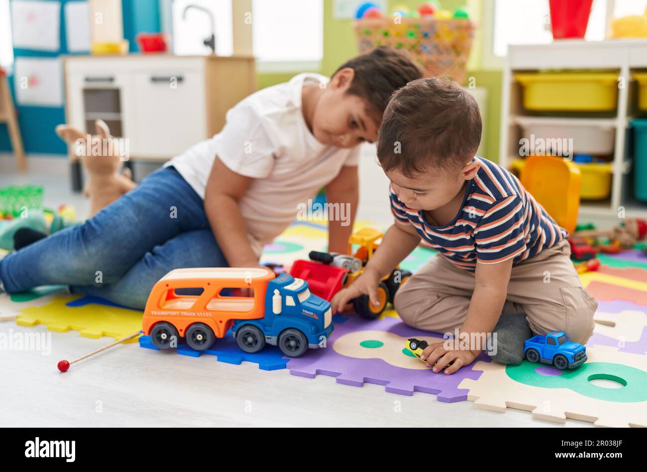 Adorable boys playing with cars toy sitting on floor at kindergarten ...
