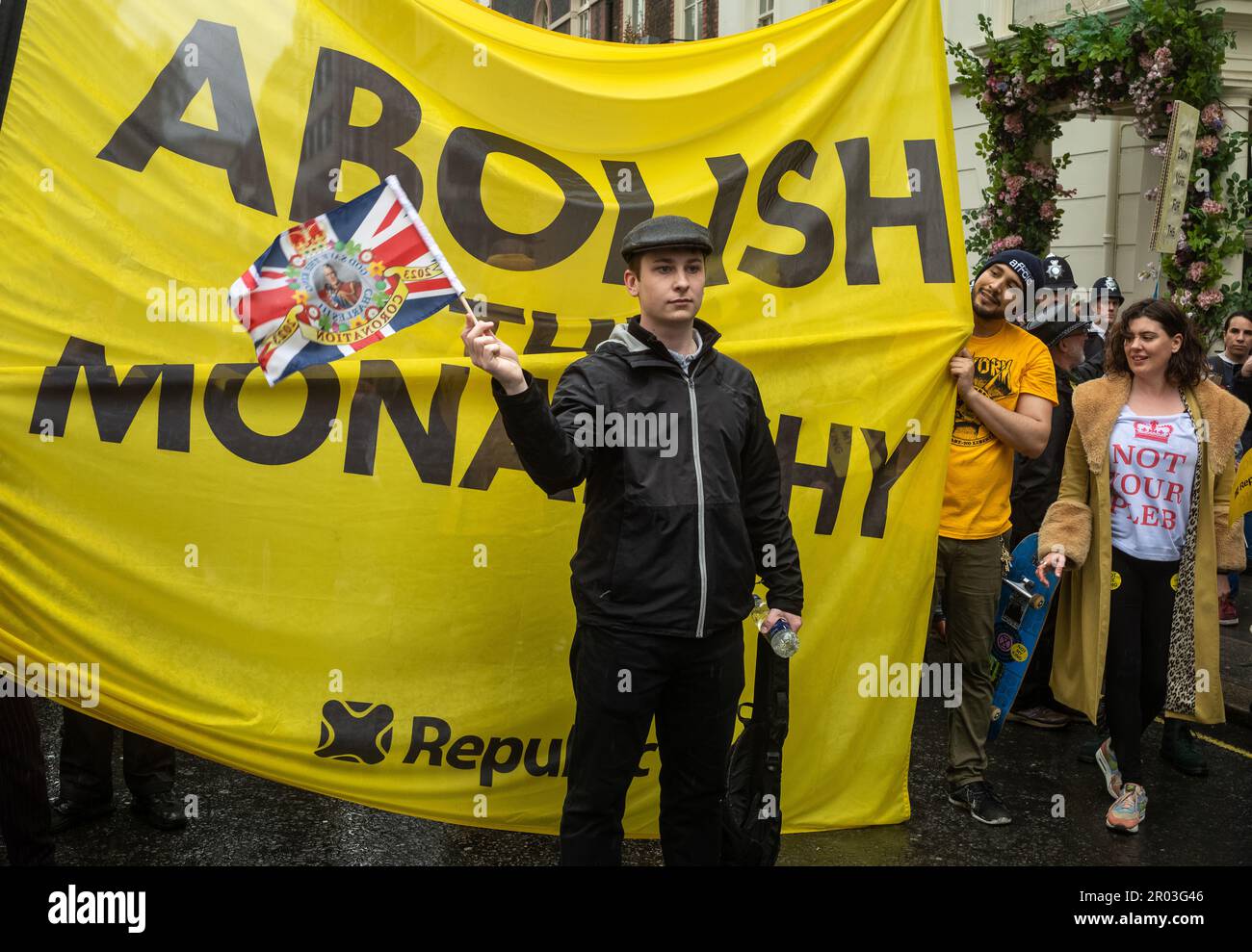 London, UK. 06th May, 2023. An anti-monarchy protestor stands in front of a large banner reading 'Abolish the Monarchy' in  in central London on 6 May, 2023, as the coronation of King Charles III took place a short distance away.    Earlier, the head of the anti-monarchist campaign group Republic and a number of activists were  arrested by police in Trafalgar Square. It was the first coronation of a new monarch in London, UK, for 70 years and despite steady rain, many thousands of people descended on the capital city to enjoy the celebrations. Credit: Andy Soloman/Alamy Live News Stock Photo