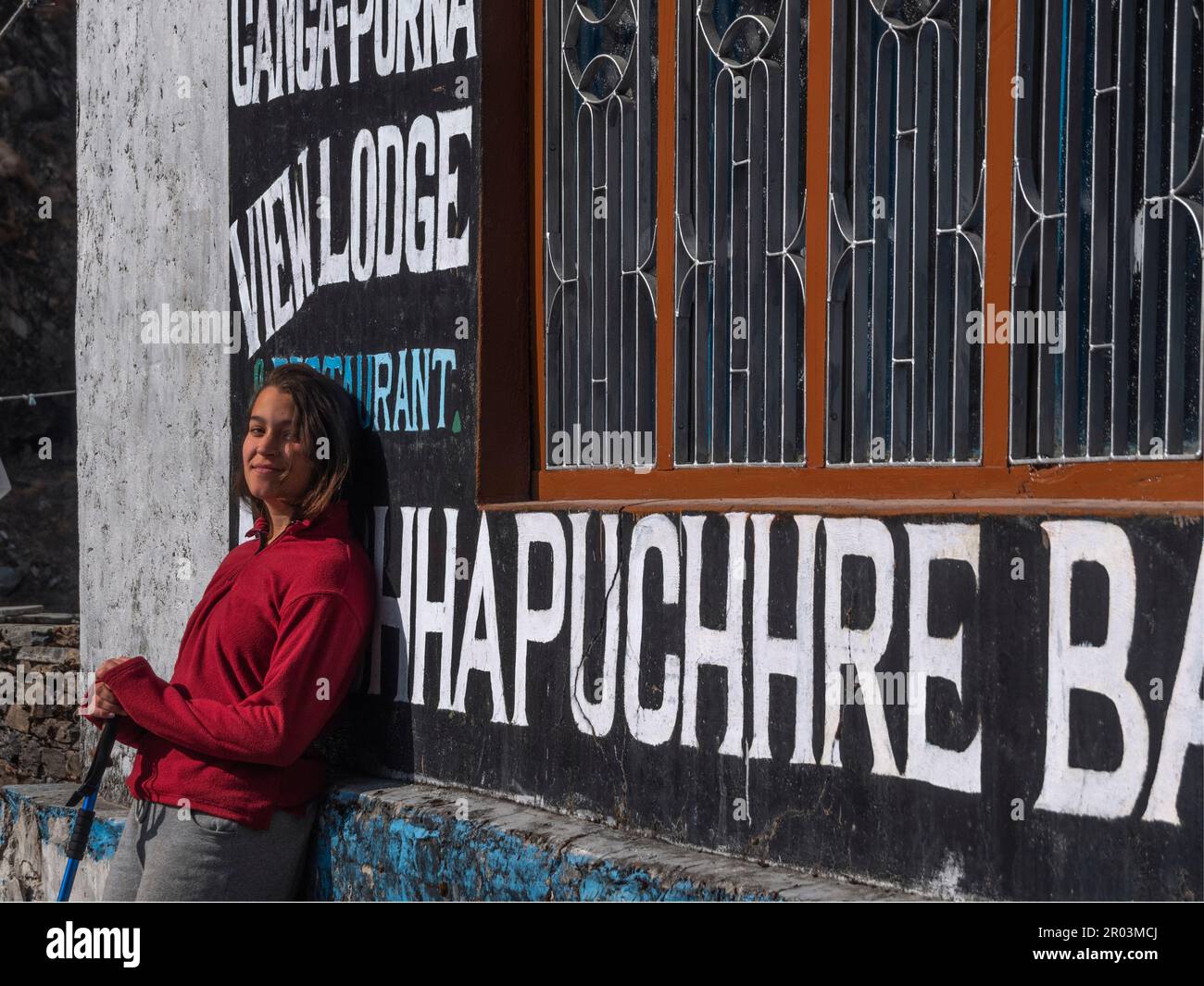 Female backpacker with red fleece jumper and trekking poles looking at camera in Machhapuchhare Base camp (Nepal). Stock Photo