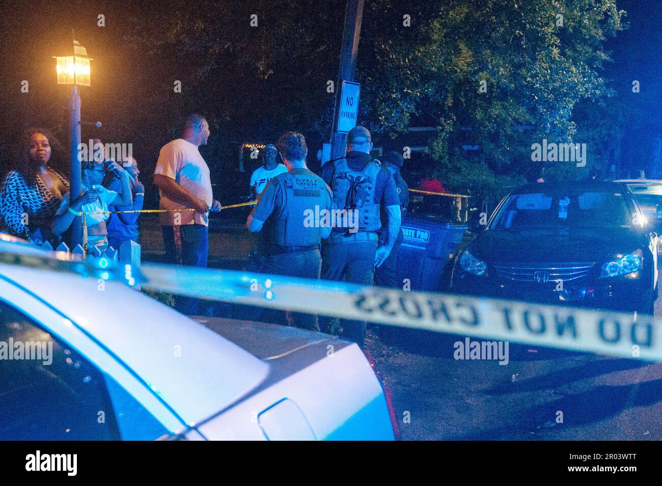 Law enforcement officers stand behind crime scene tape as onlookers