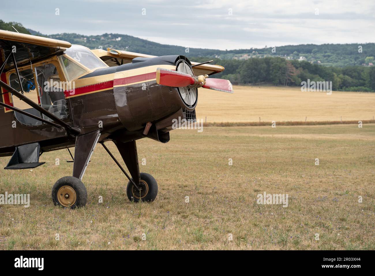 Detail of a classic airplane on the field. Biplane. Nine cylinder radial engine. Countryside in the background. Stock Photo