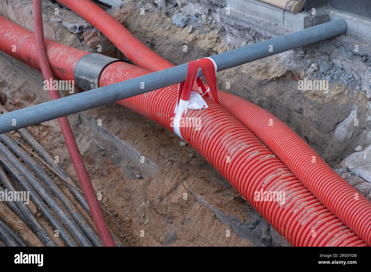 Electric cables in red corrugated pipe are buried underground on the
