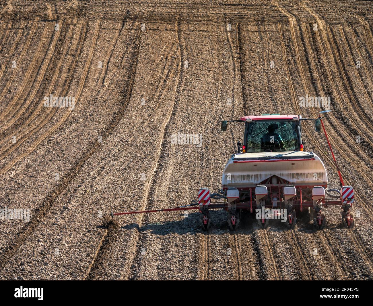 Arable field being planted by sowing machine Stock Photo