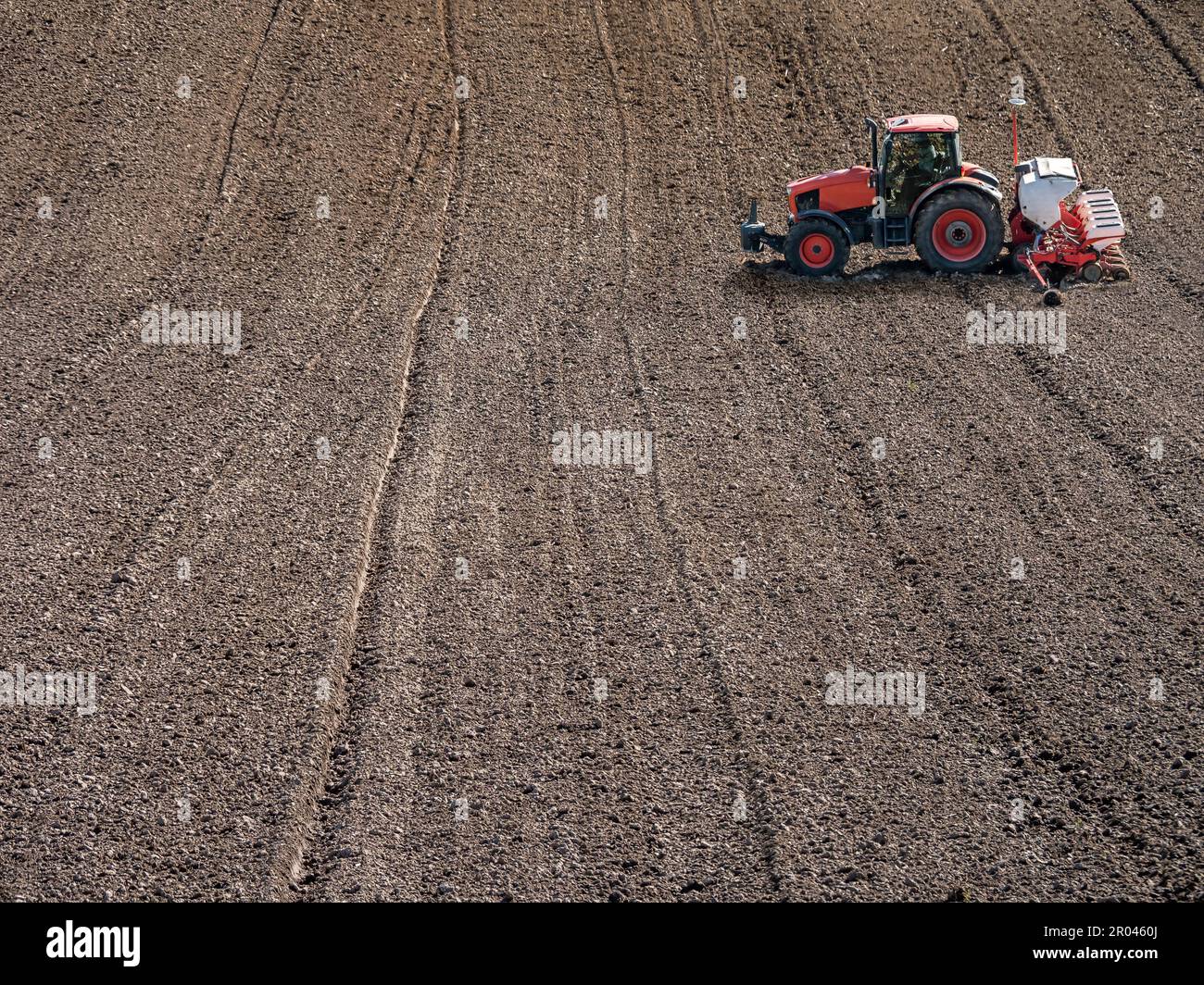 Arable field being planted by sowing machine Stock Photo