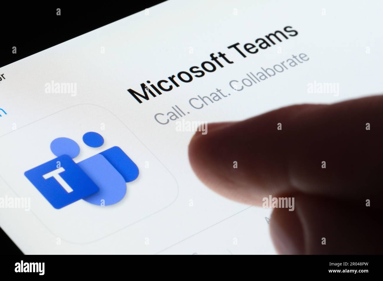Microsoft Teams app seen in App Store on the screen of ipad and blurred finger pointing at it. Selective focus. Stafford, United Kingdom, May 6, 2023 Stock Photo