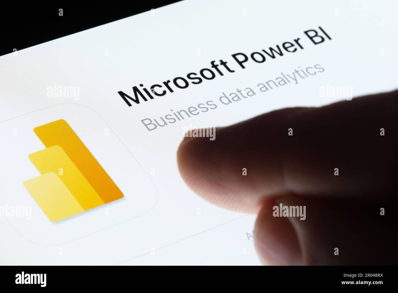 Microsoft Power BI app seen in App Store on the screen of ipad and blurred finger pointing at it
