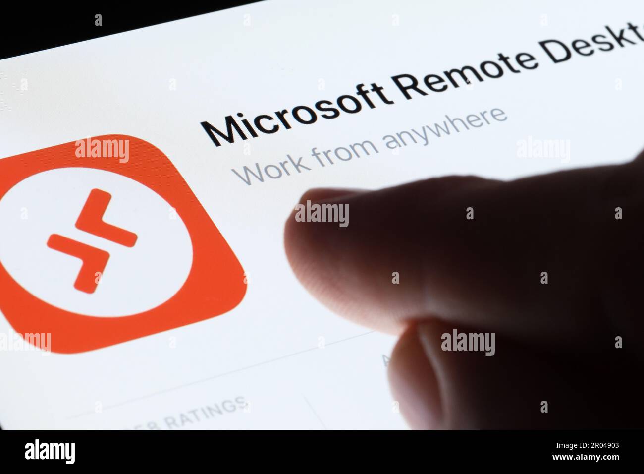 Microsoft Remote Desktop app seen in App Store on the screen of ipad and blurred finger pointing at it. Selective focus. Stafford, United Kingdom, May Stock Photo