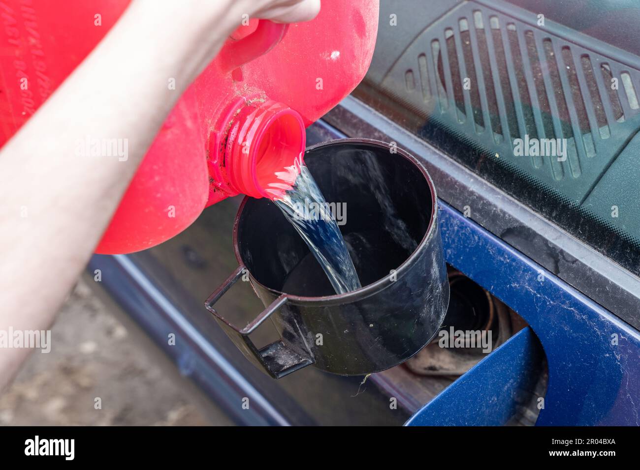 Pouring fuel with funnel in a car gas tank from red can Stock Photo Alamy
