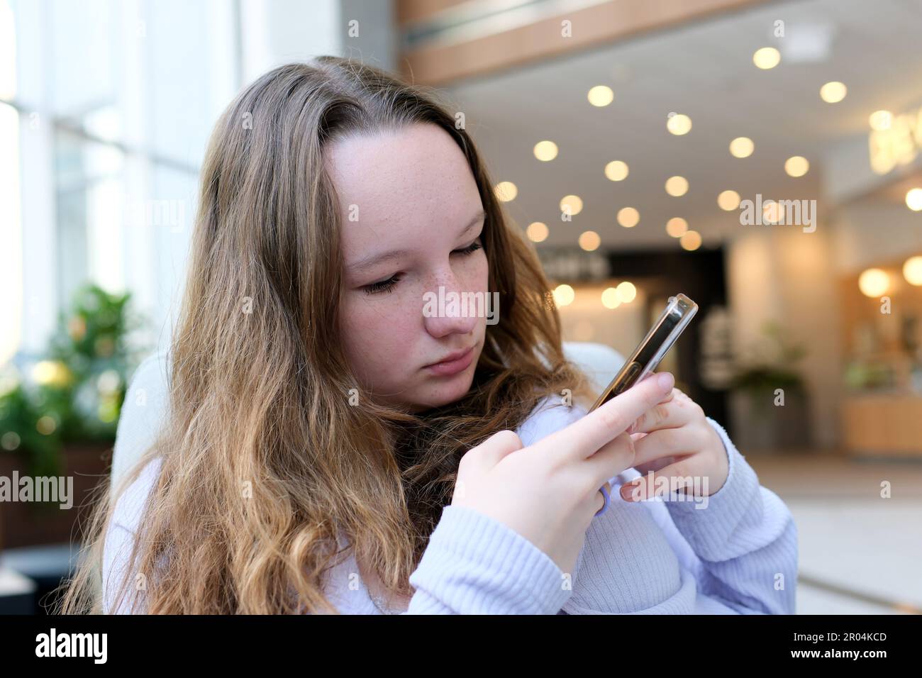 Beautiful cute young teenage girl looks at the phone and takes photo of