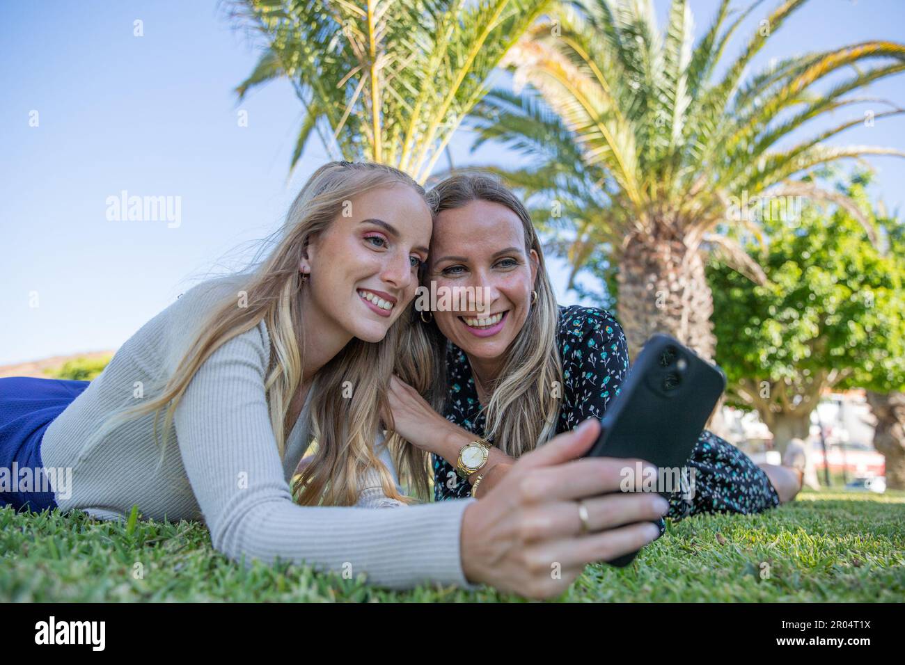 Mother and daughter take a selfie while lying in a meadow together Stock Photo