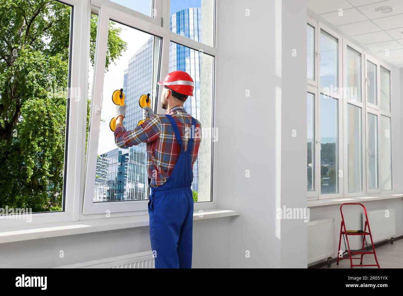 Worker using suction lifters during plastic window installation indoors Stock Photo