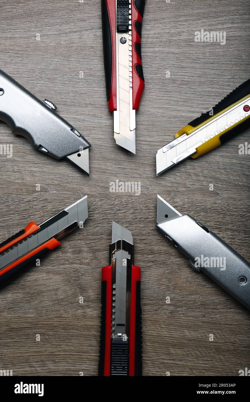 Many different utility knives on wooden table, flat lay Stock Photo
