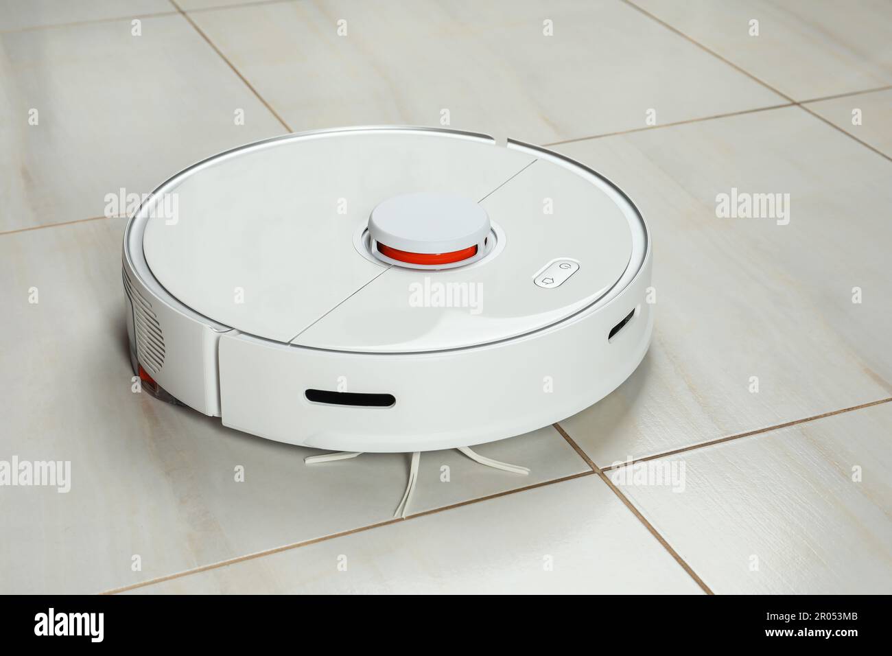 Robotic vacuum cleaner on white tiled floor Stock Photo