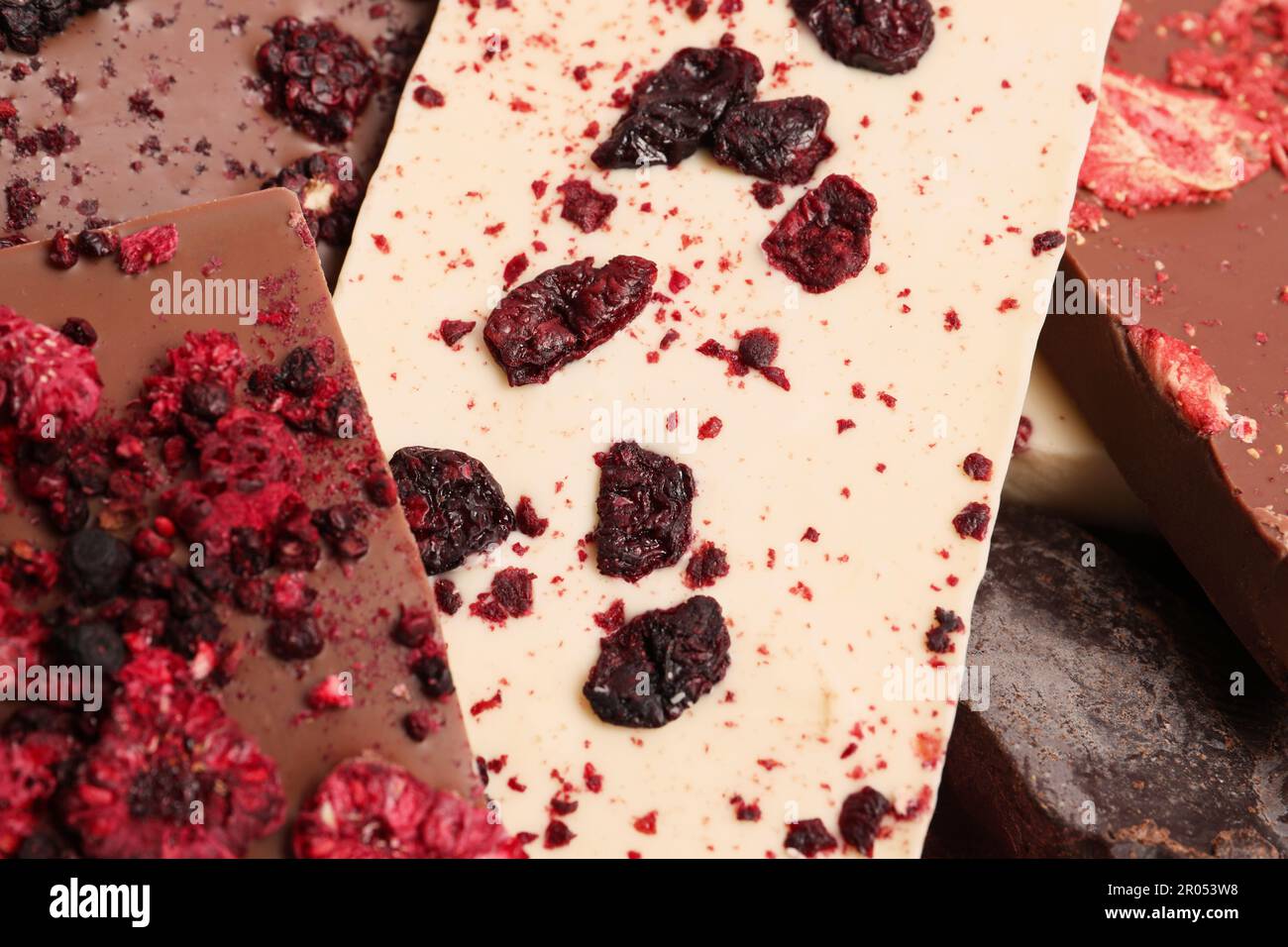 Different chocolate bars with freeze dried fruits as background