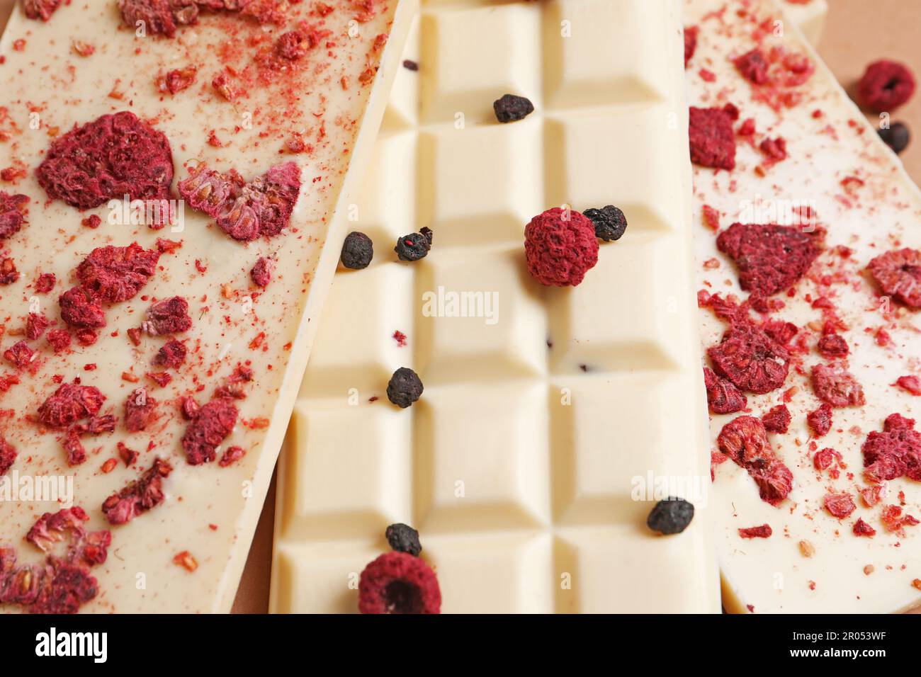 White chocolate bars with freeze dried fruits as background, closeup ...