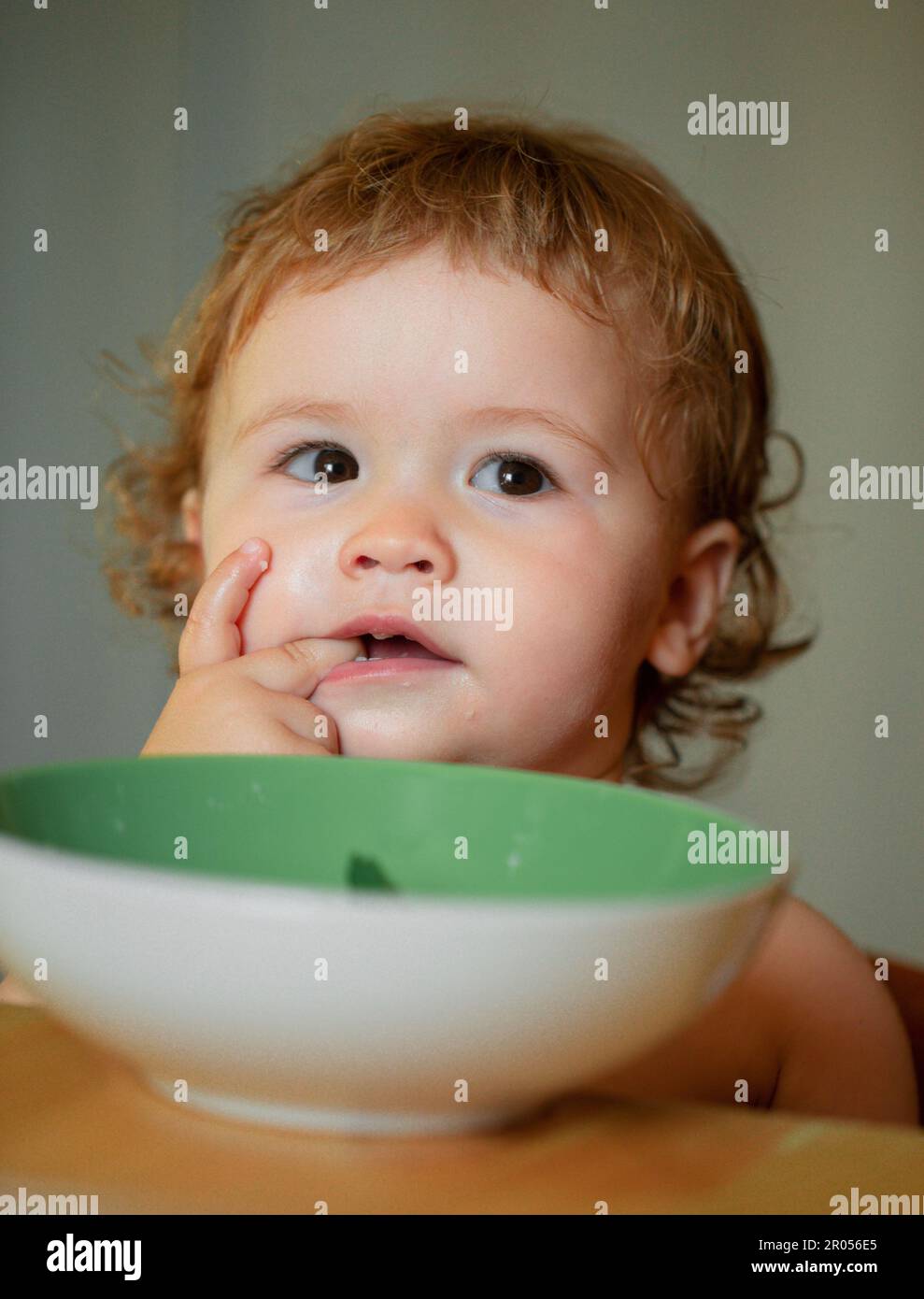 Kid baby eat soup in the kitchen with dishes and spoon. Lick tasty