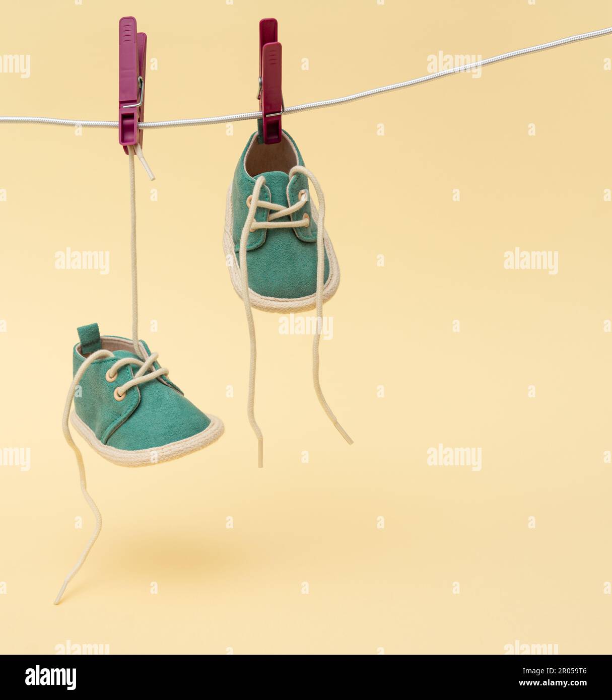 Tiny baby shoes hanging on the clothesline. Newborn concept Stock Photo